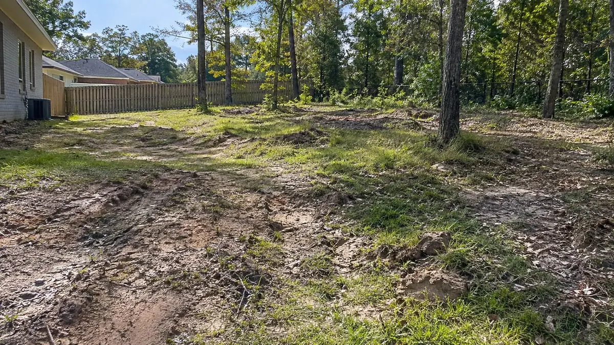 Rutted, muddy backyard with low spots and standing water damage before yard grading in the Pensacola FL area