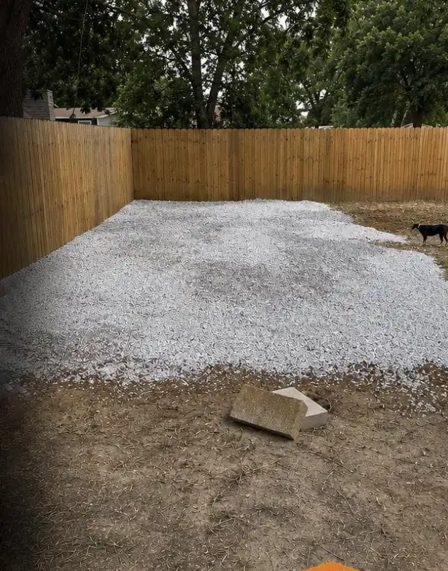 Finished gravel parking pad spread level inside a privacy fenced backyard